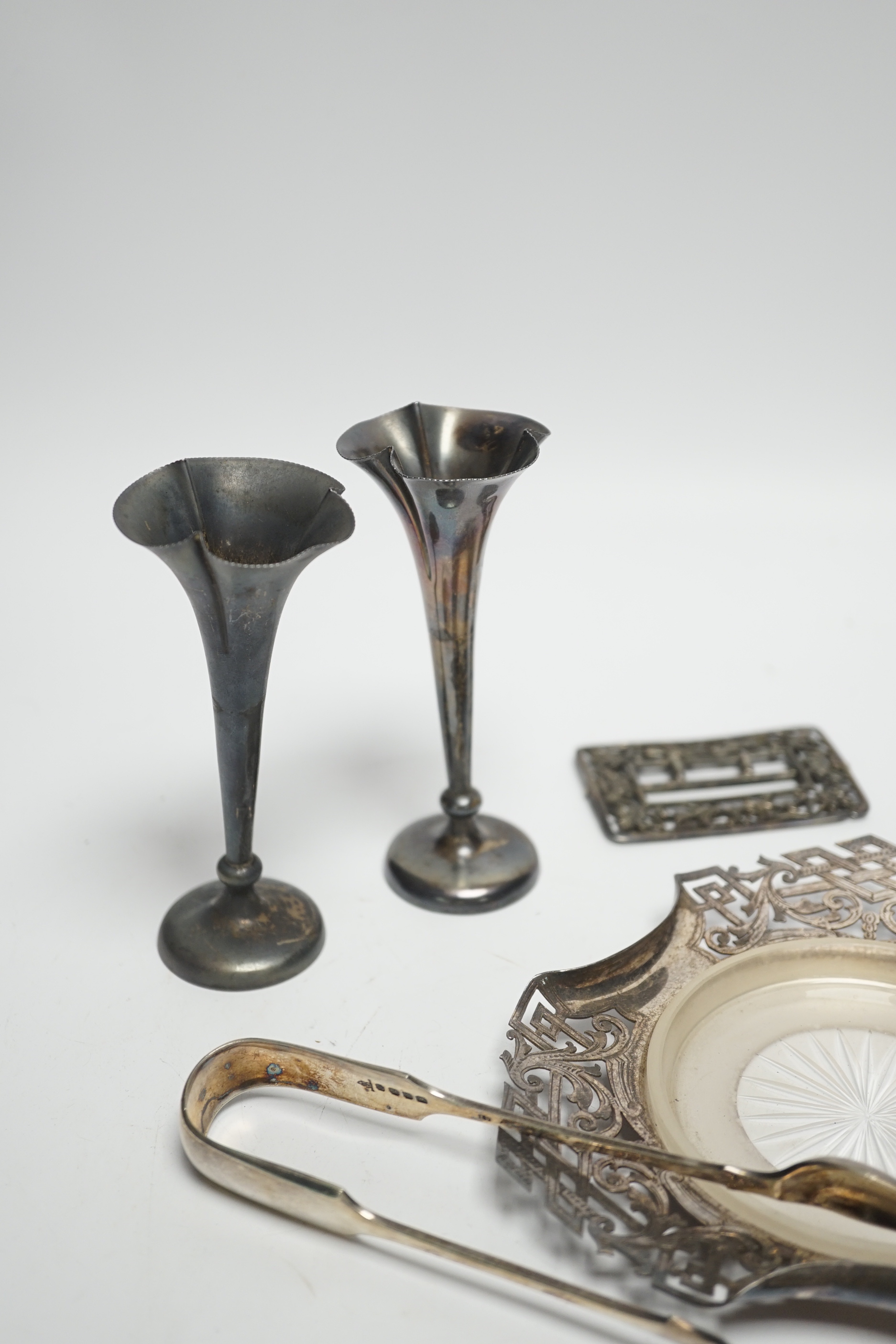 A pair of Edwardian silver mounted posy vases, Birmingham, 1902, weighted, 11.1cm, a silver purse, two silver napkin rings, silver butter dish stand, a silver belt buckle and a pair of plated sugar tongs.